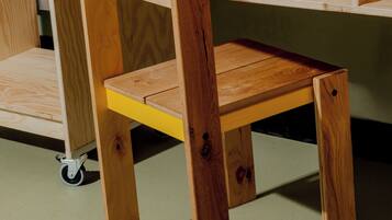 A wooden desk with a yellow shelf and a chair.