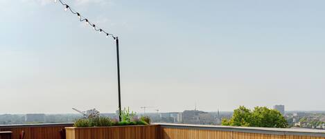 Terraza en la azotea con piso de madera, jacuzzi y mobiliario exterior.