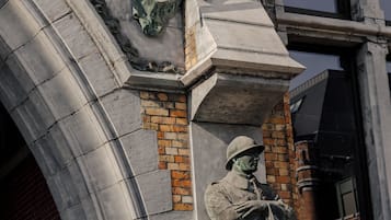 Detallada escultura en relieve de piedra en la fachada de un edificio, con figuras con vestimenta de época.