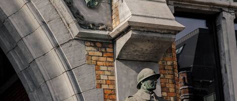 Detallada escultura en relieve de piedra en la fachada de un edificio, con figuras con vestimenta de época.