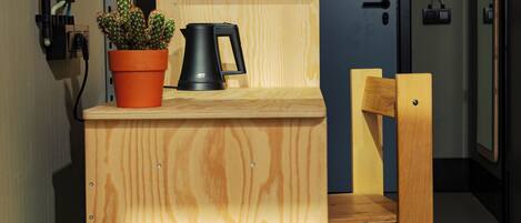 A wooden counter with a potted cactus and a black coffee maker.