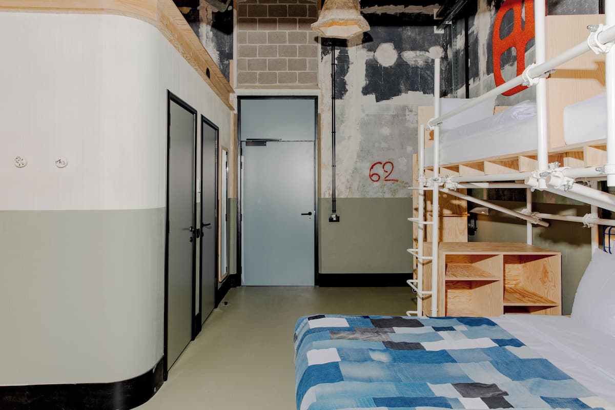 A dormitory room with bunk beds, a door, and a wall with a number '62'.