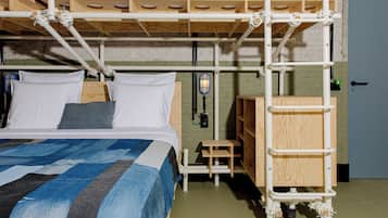 Un letto a castello con una scaletta in legno, un tavolino di legno e un faretto fissato al muro.
