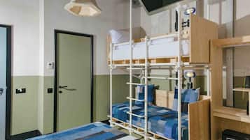 Una cama litera con estructura de madera, una mesita de noche, una lámpara y un televisor montado en la pared.