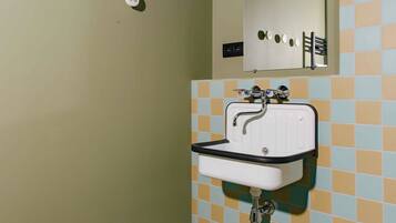 Une salle de bain avec un lavabo blanc, un miroir et un mur recouvert de carreaux.