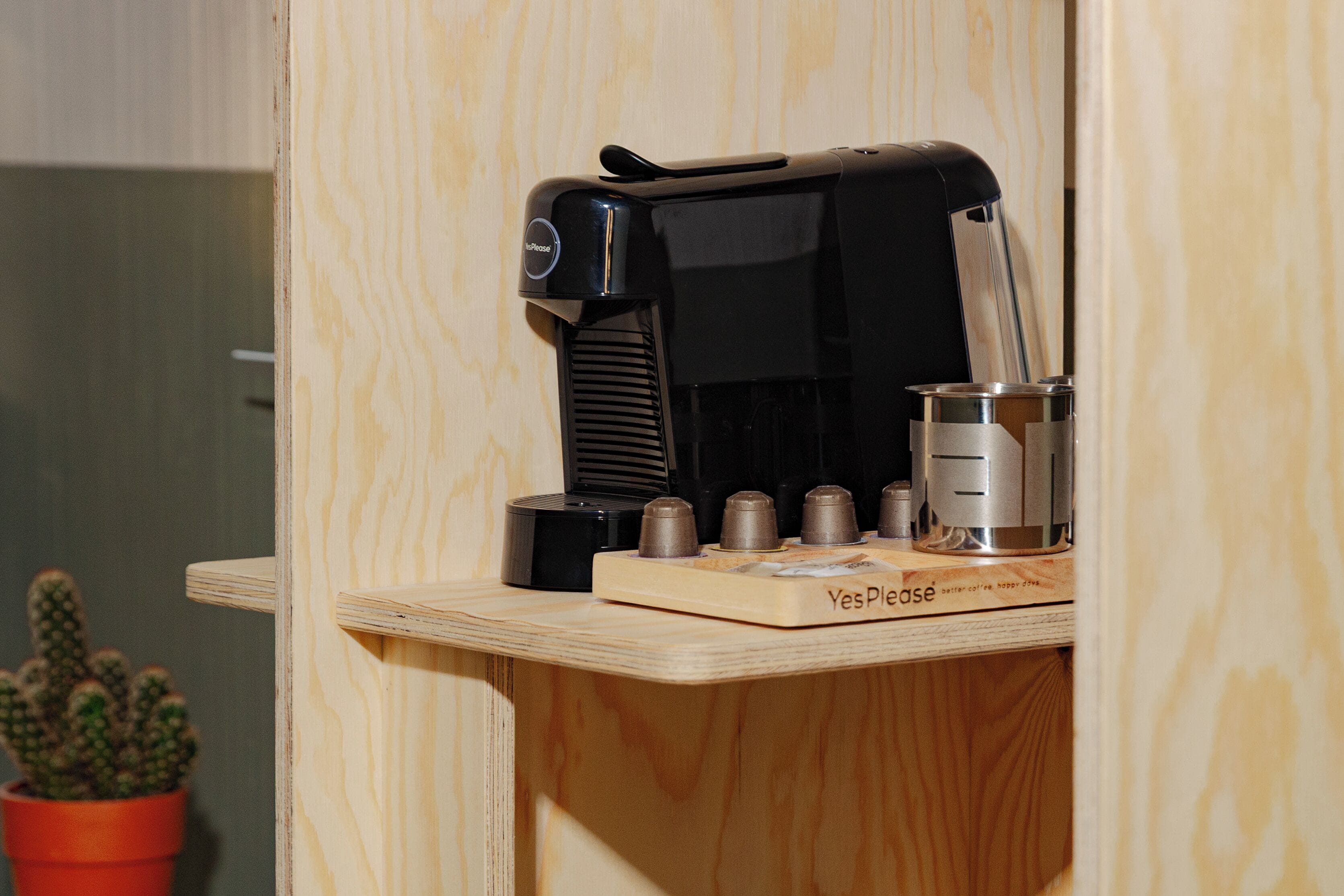 A coffee machine on a wooden counter with a Yes Please coffee mug holder.