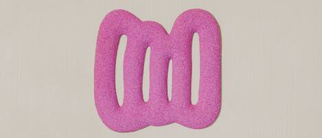 A bed with white bedding and pillows, a wooden headboard, and a pink abstract wall decoration.