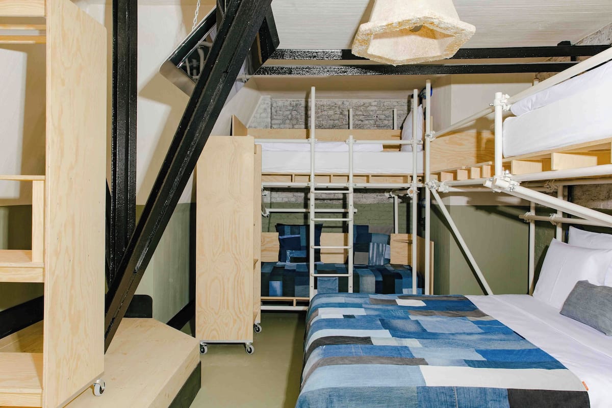 A bunk bed room with a wooden ladder, a desk, and a storage unit.