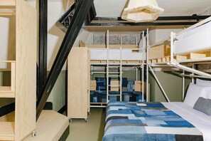 Habitación con literas, una escalera de madera, un escritorio y un espacio de almacenamiento.