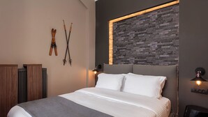 Een moderne slaapkamer met een groot bed, een houten hoofdeinde en een wand met stenen accenten.