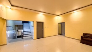A spacious hallway with a staircase leading to a room, a door, and a couch. - Hotel Diamond Palace (Varanasi)