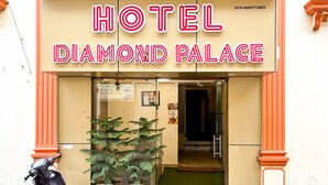 The entrance to Hotel Diamond Palace with a clear sign, a glass door, and a potted plant outside. - Hotel Diamond Palace (Varanasi)