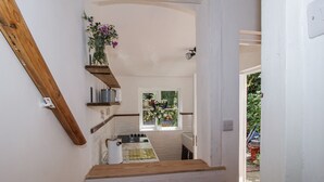 A narrow kitchen with wooden shelves, a window with a view, and a small countertop. - 157 Watling Street South (Church Stretton)