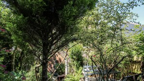 A garden with a stone pathway leading to a wooden bench and a small table. - 157 Watling Street South (Church Stretton)