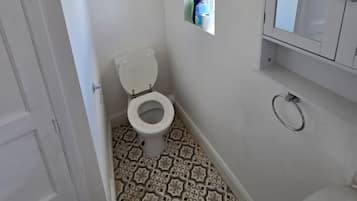 A small bathroom with a toilet, a mirror, and patterned floor tiles.