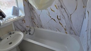 Une salle de bain avec une baignoire, un lavabo et une fenêtre en verre dépoli.