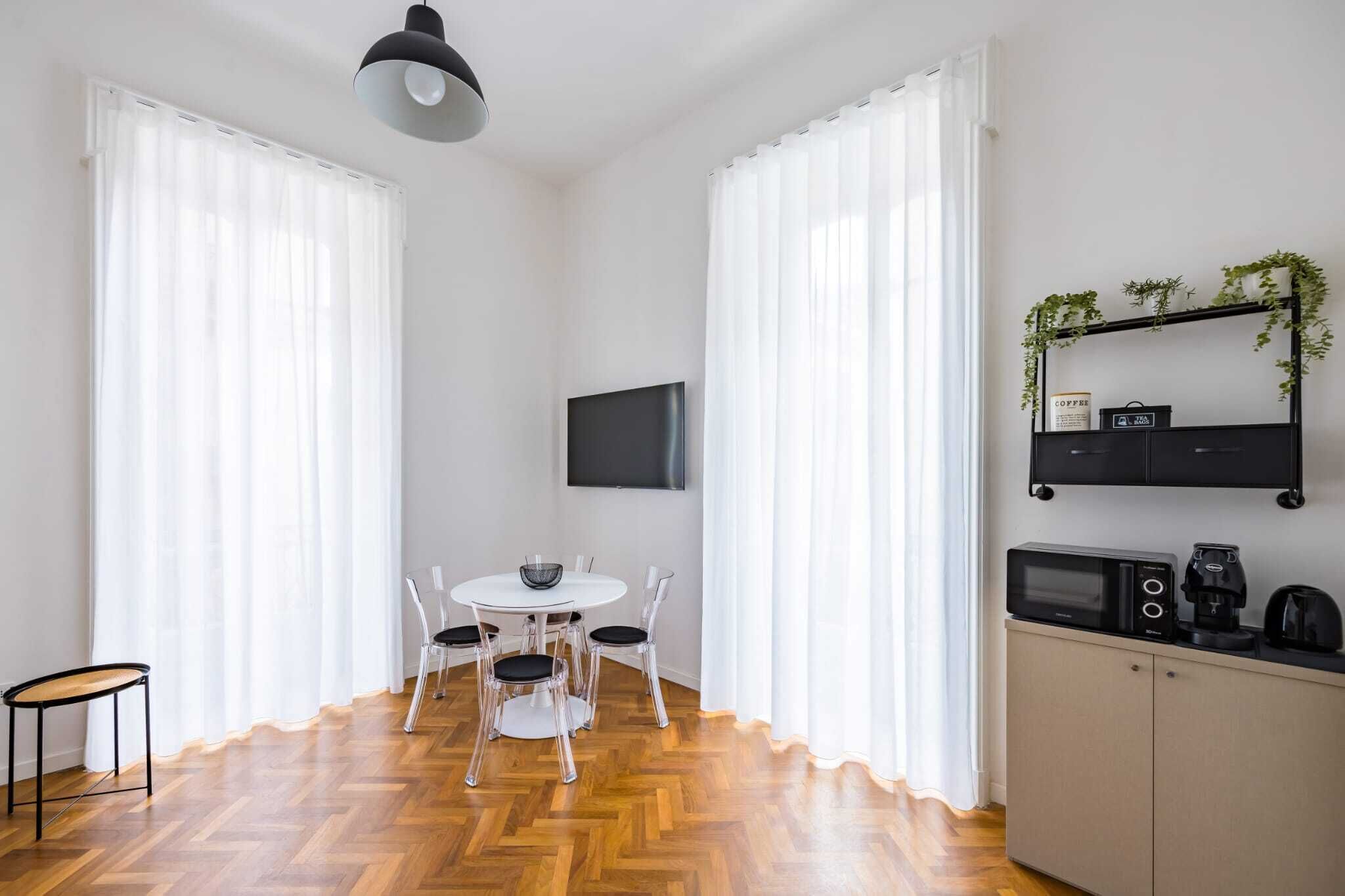 A modern kitchen with a microwave, coffee maker, and a shelf with plants.