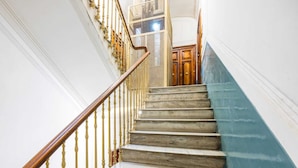 Una escalera de mármol con barandilla de madera y una pared azul decorativa.