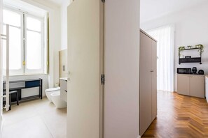 Une salle de bain moderne et bien éclairée, équipée de toilettes, d’un lavabo et d’un meuble de rangement.