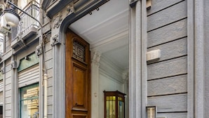 Entrada de un edificio con puerta de madera, fachada de piedra y un pequeño balcón.