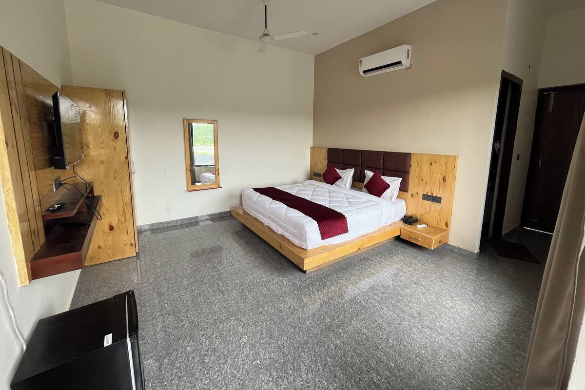 Ein Schlafzimmer mit einem Bett, Deckenventilator, Klimaanlage, Holzschrank, Spiegel und Schreibtisch mit Stuhl.