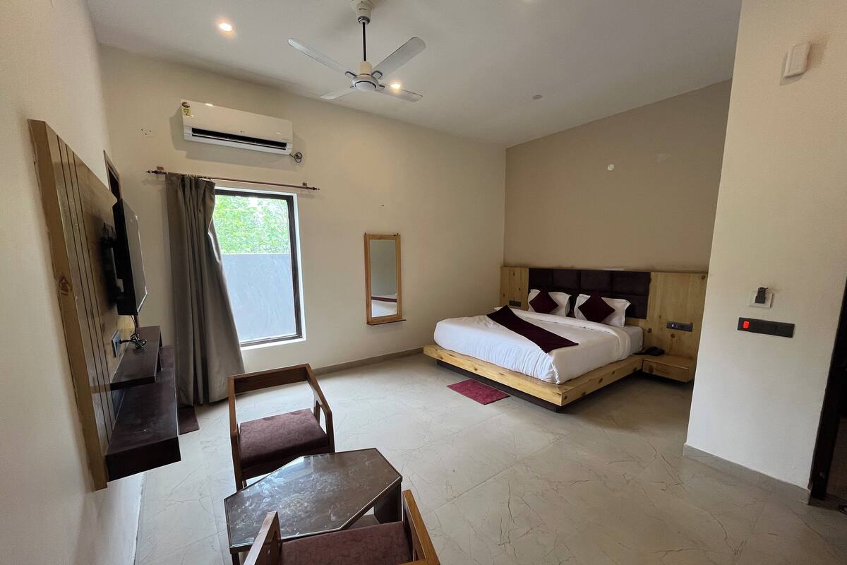 Ein Schlafzimmer mit Bett, Schreibtisch, Stuhl, Klimaanlage, Deckenventilator und Fenster.