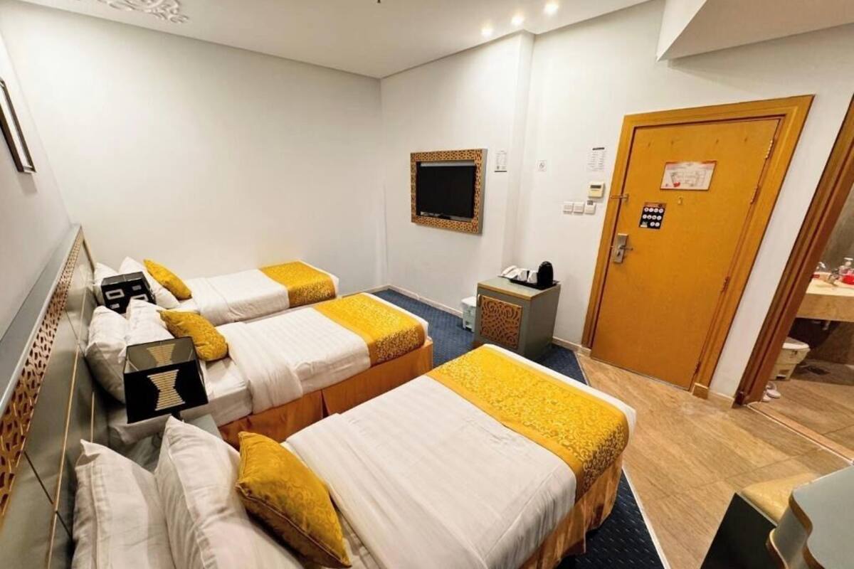 A hotel room with two beds, a TV, a desk, and a door.