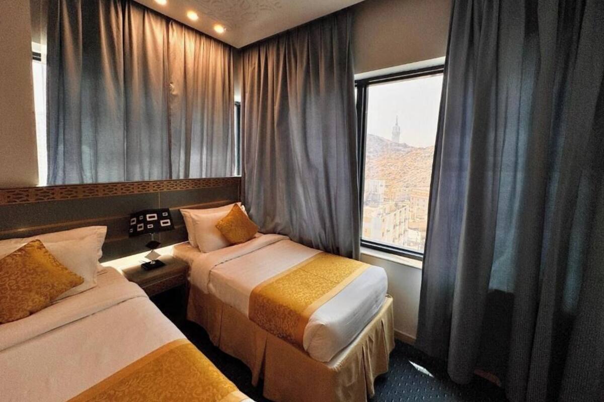 A hotel room with two beds, a nightstand, and a window with curtains.