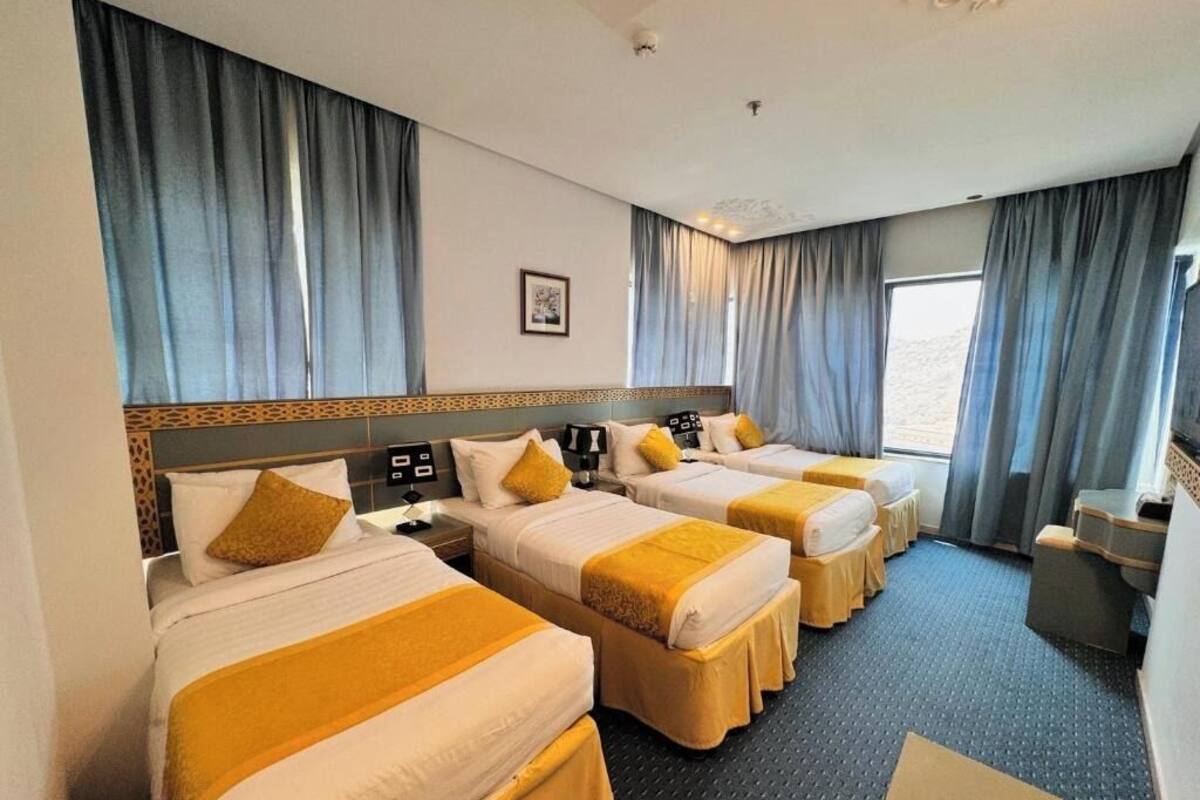 A hotel room with three beds, a desk, and a chair.