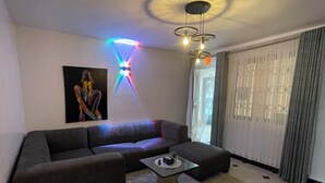 A modern living room with a sectional sofa, a glass coffee table, and a patterned rug.