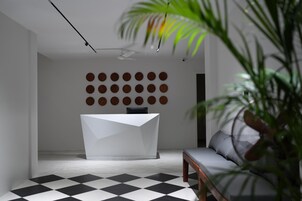 A modern reception area with a white reception desk, a patterned floor, and a wall with circular decorations.