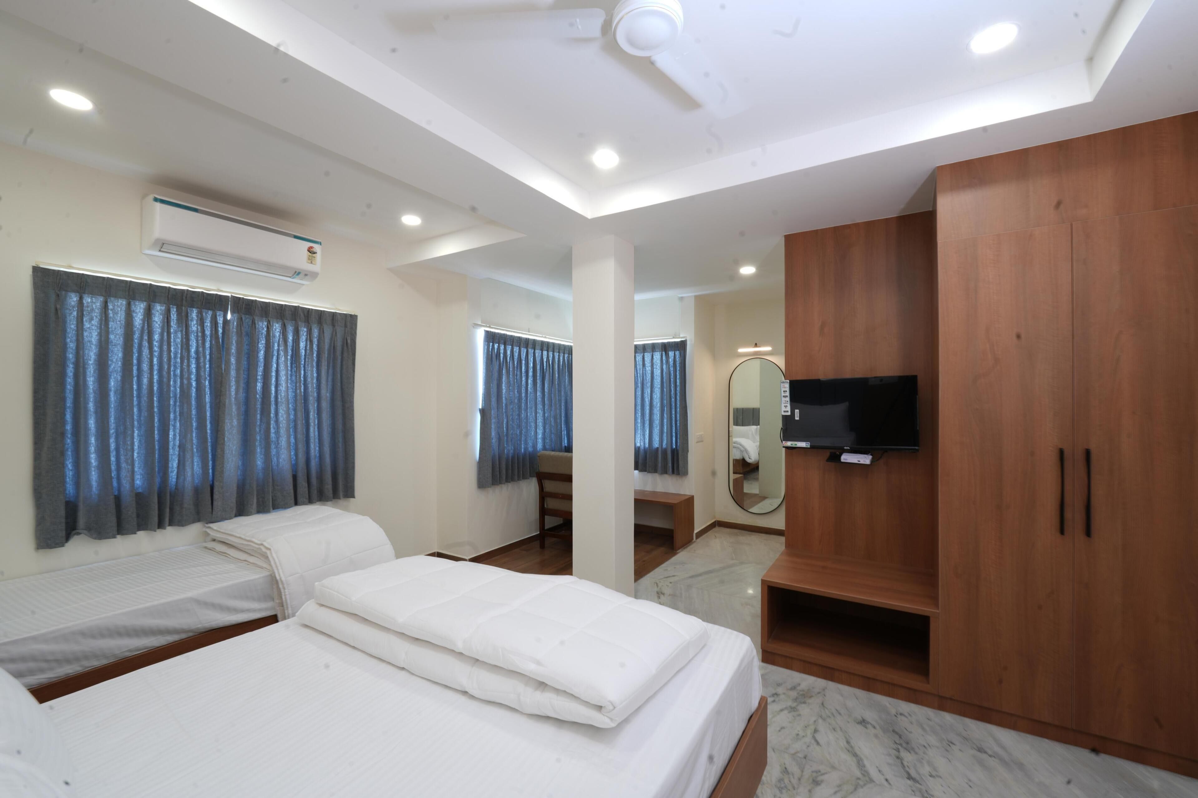A hotel room with two beds, a TV, a mirror, and a wardrobe.