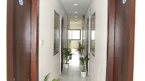 Un pasillo con puertas de madera, plantas en macetas y cuadros en las paredes.