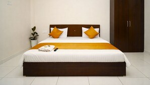 Una cama bien hecha con cabecera de madera, dos almohadas y una colcha.