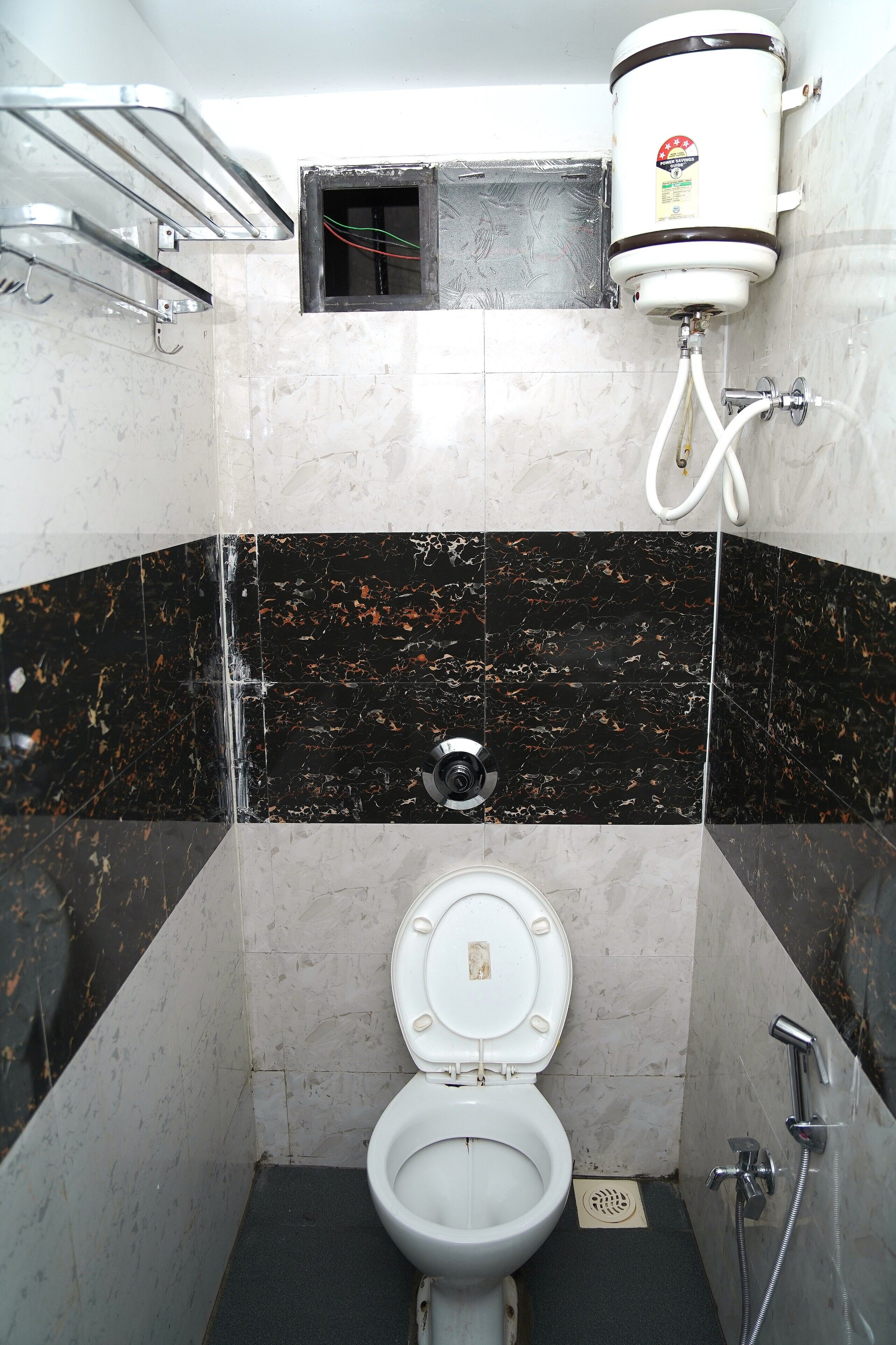 A bathroom with a toilet, a water heater, and a shower.