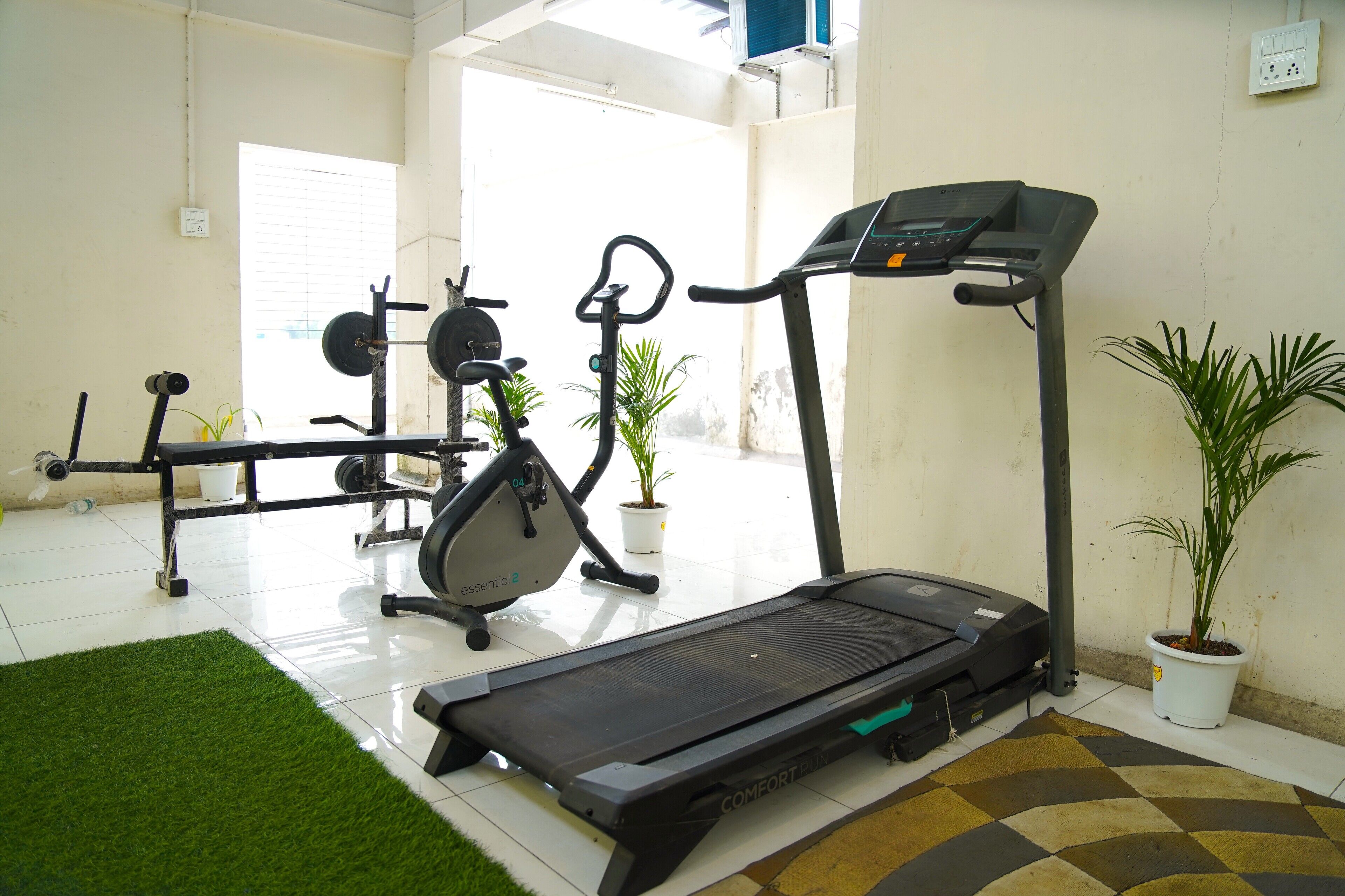 A home gym with a treadmill, elliptical, and weight bench.