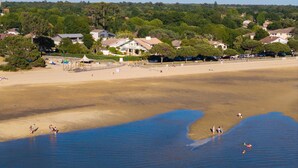 A beach with houses in the background and people in the water.