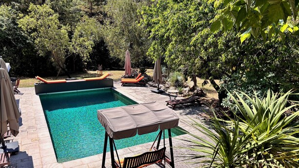 A rectangular pool with a tiled deck, surrounded by lounge chairs and umbrellas. - Ekin Ô reV (Montauroux)