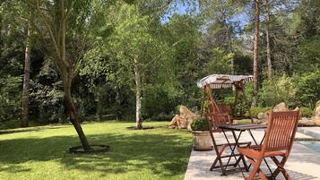 Un patio con mesa y sillas de madera, y un toldo a rayas.