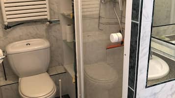 A bathroom with a toilet, a shower enclosure, and a marble-tiled wall.