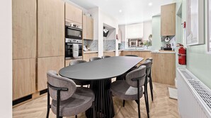 Een moderne keuken met houten kastjes, een centraal eiland en een eetgedeelte met grijze stoelen.