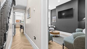 Een moderne woonkamer met een grijze bank, een salontafel en een flatscreen televisie die aan de muur is bevestigd.