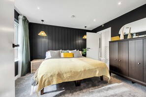 Ein Schlafzimmer mit Bett, Nachttischlampen, einem Kleiderschrank und einem Fenster mit Vorhängen.