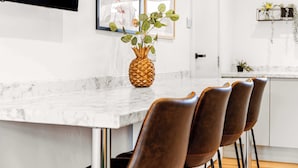 A kitchen with a marble countertop, a pineapple centerpiece, and brown chairs.