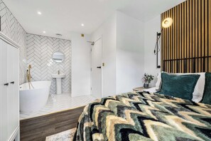 Ein modernes Schlafzimmer mit einem großen Bett, einer integrierten Badewanne und einer Wandpaneelung aus Holz.