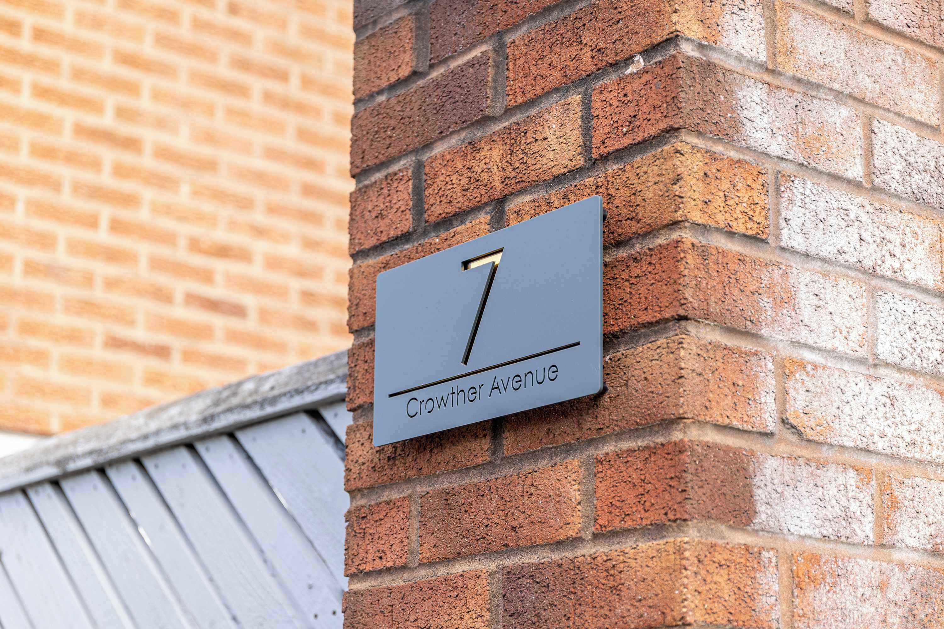A house number sign on a brick wall.