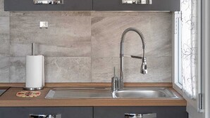 Una cocina moderna con armarios oscuros, un lavamanos de acero inoxidable y una ventana con cortinas florales.