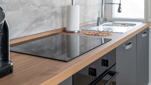 Una cocina moderna con encimera de madera, estufa integrada, un fregadero y un ventanal que proporciona luz natural.