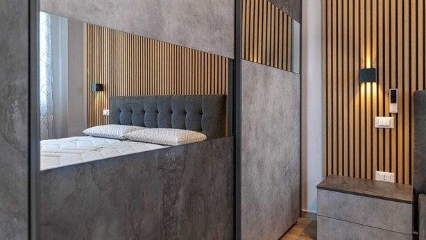 Un dormitorio moderno con un cabecero acolchado, un espejo grande y un diseño de pared con listones de madera.