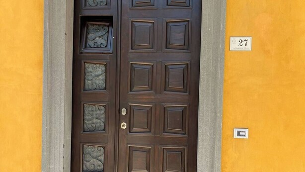 Eine braune Tür mit dekorativen Glasfeldern und einer Hausnummer.